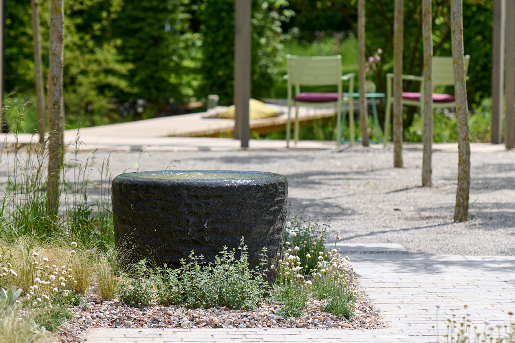 Muschelkalkbrunnen rund, mit Katzenminze (Nepeta) umpflanzt.