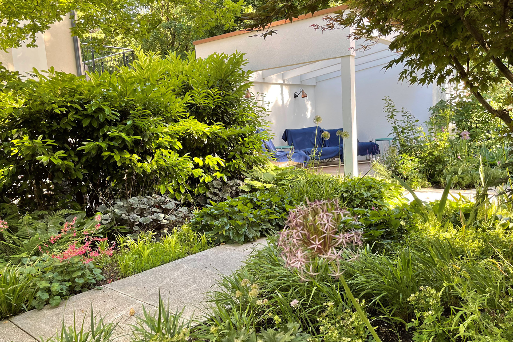 Blick in die überdachte Gartenlounge, im Vordergrund ein Granitweg